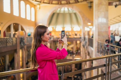 Frau Influencerin in pinkfarbenem Kleid in Kaufhaus macht Selfie