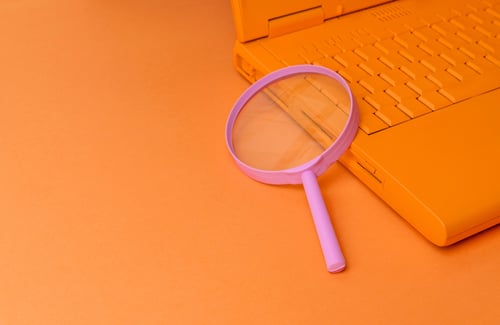 rosa Vergrößerungsglas auf Laptop Tastatur in orange