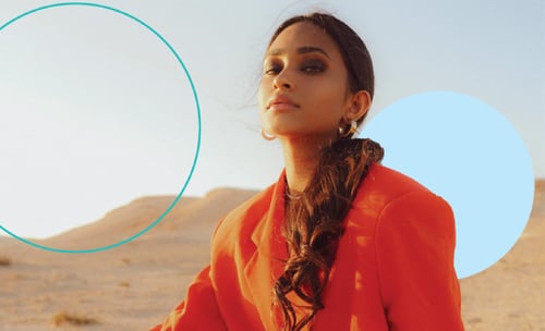 modebewusst in Orange gekleidete Dame mit langem braunen Pferdeschwanz in Wüste