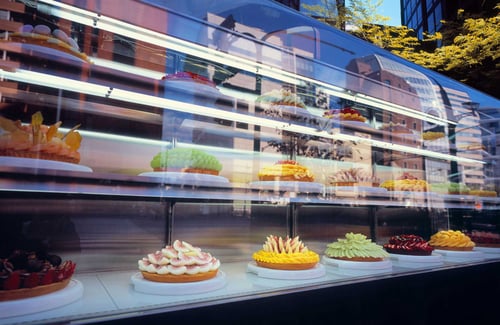 Auslage einer Bäckerei im Freien mit einer großen Auswahl an bunten, frischen Torten mit Obst.